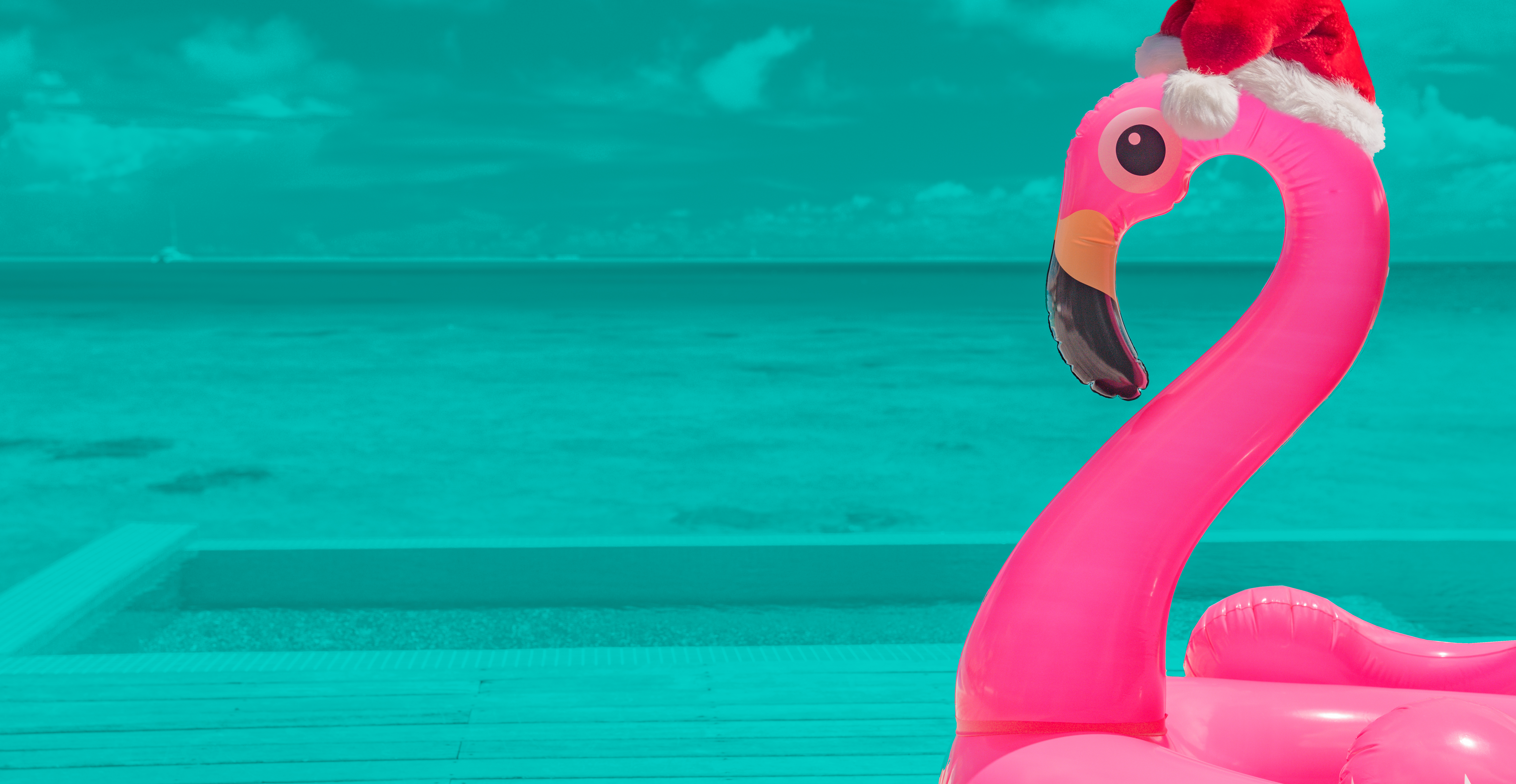 Image of inflatable Flamingo wearing a Santa hat with a beach scene background